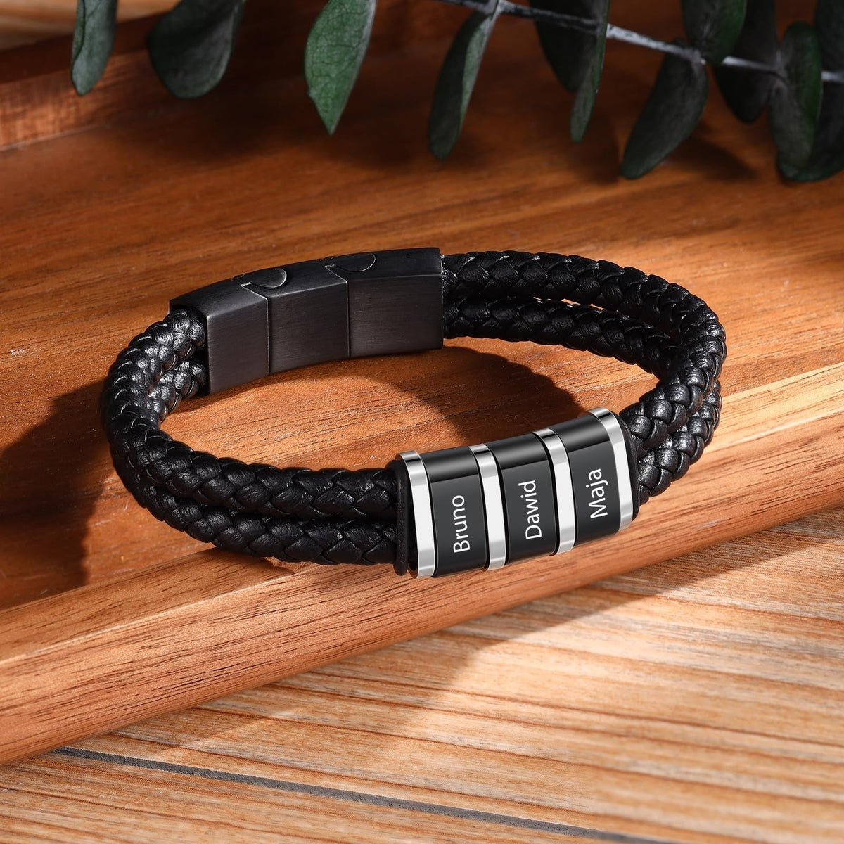 Bracelet double cordon cuir noir tressé avec quatre plaques métalliques gravées, fermoir magnétique noir mat.