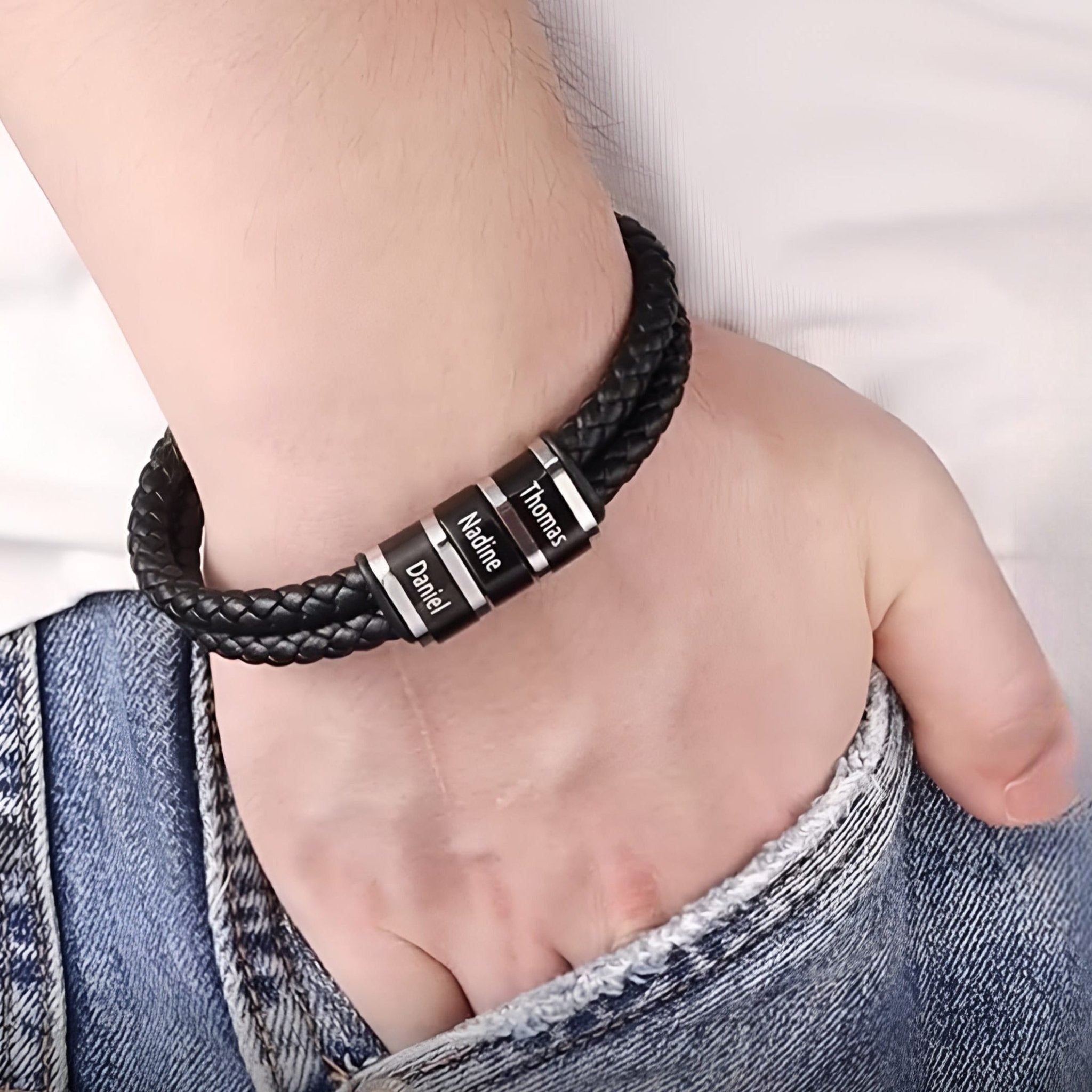 Bracelet noir double cordon en cuir tressé avec cinq plaques métalliques personnalisables porté au poignet.