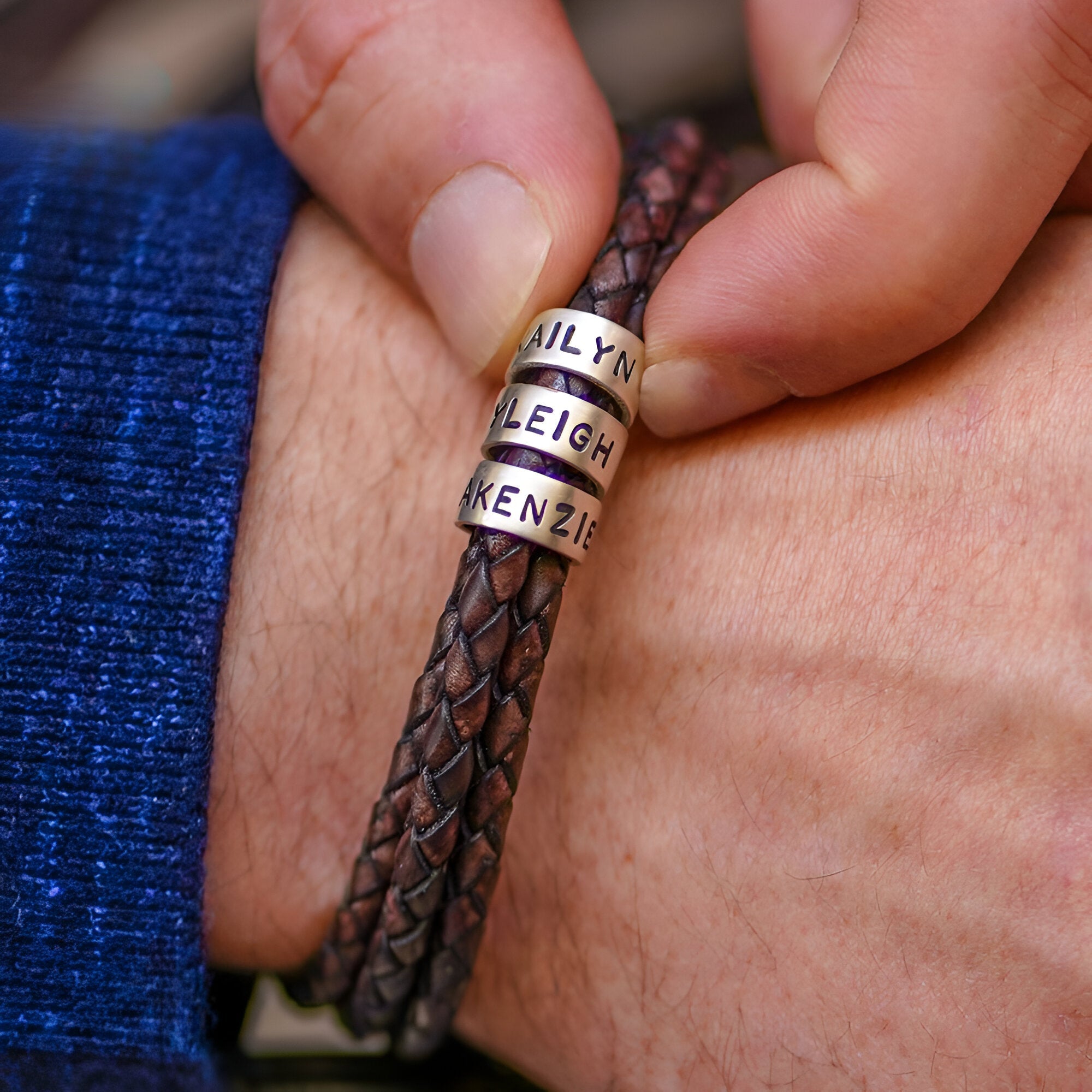 Bracelet double cordon en cuir tressé café avec trois plaques métalliques arrondies gravées de prénoms.