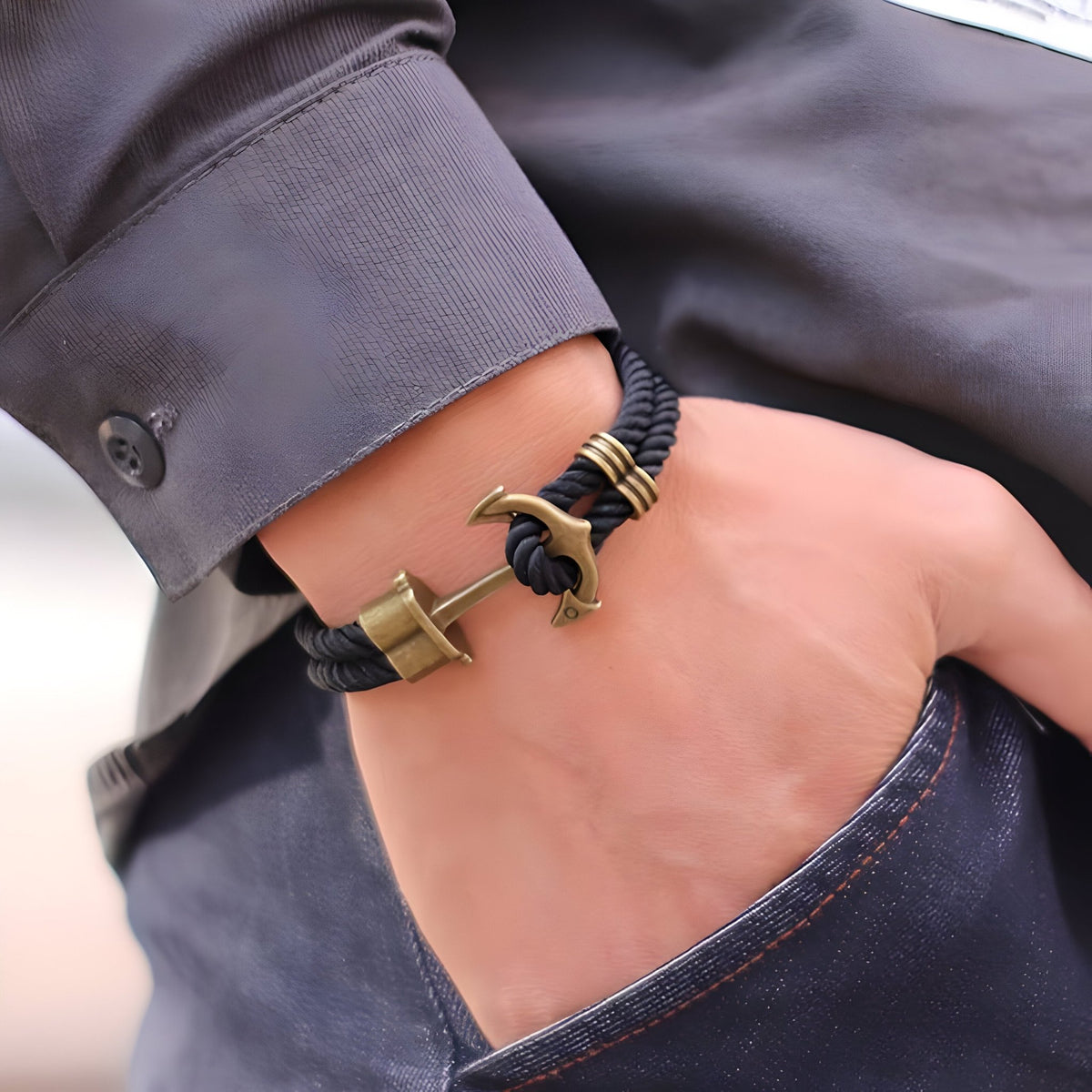 Bracelet double cordon noir avec motif ancre antique en métal bronze, style marin, porté au poignet.