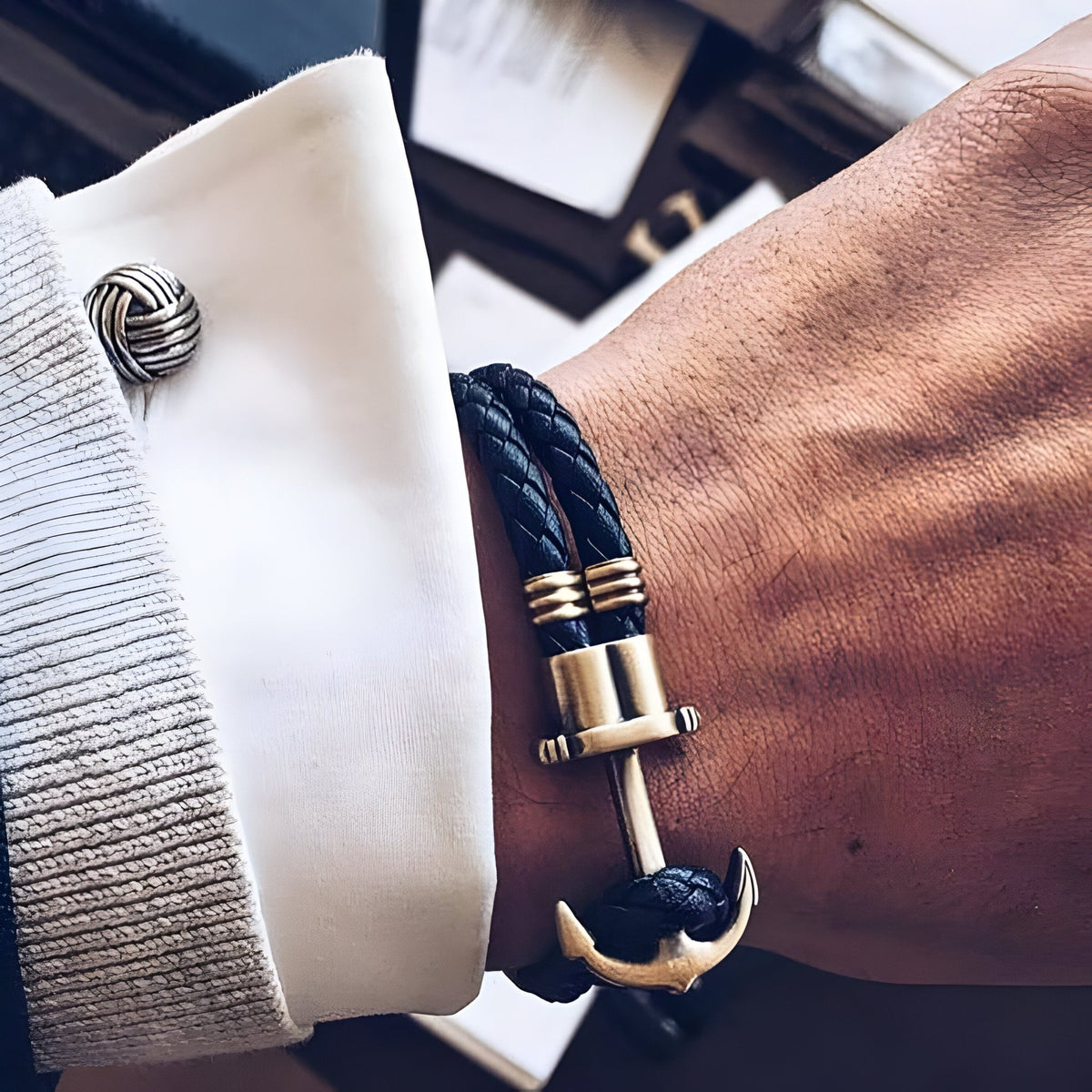 Bracelet double cordon noir tressé avec motif ancre antique dorée sur poignet.