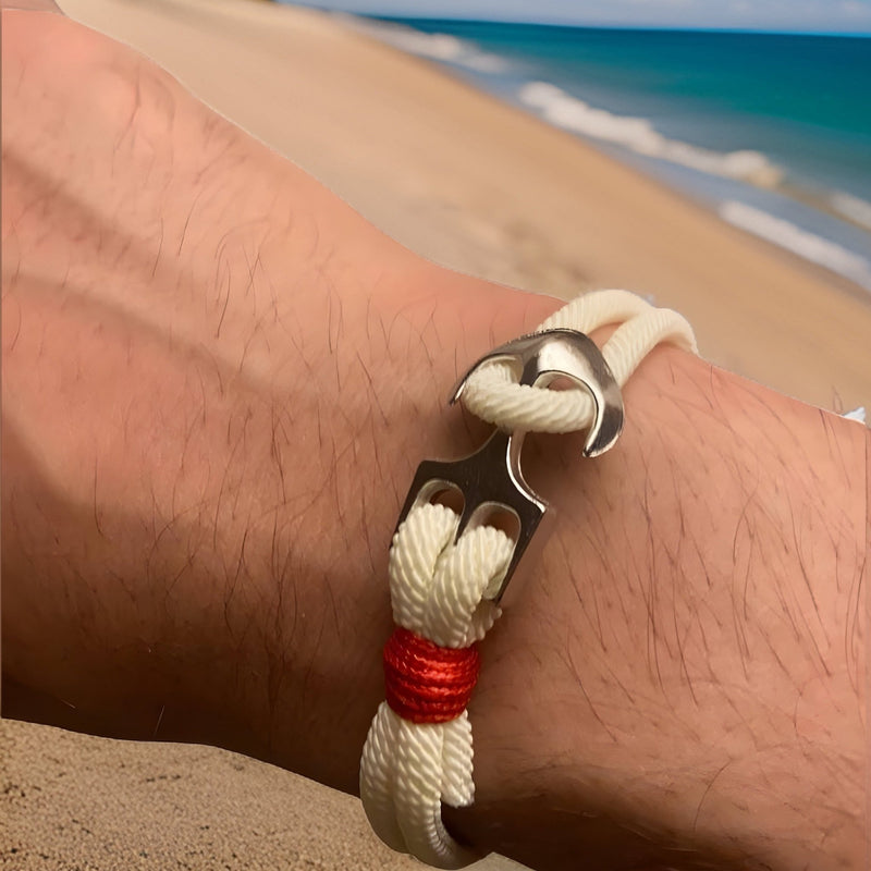Bracelet double cordon blanc avec motif ancre large en métal argenté et détail rouge au bord.