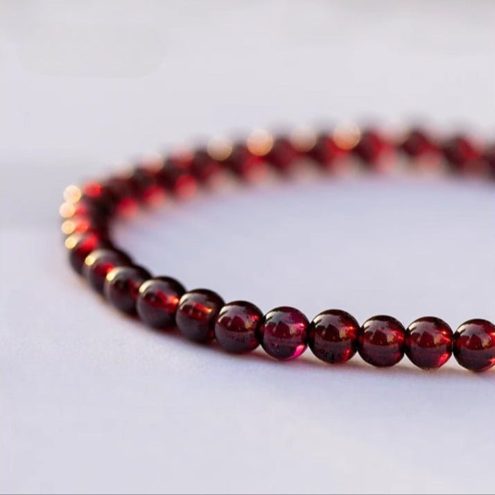 Bracelet double en perles rondes grenat rouge profond aux reflets brillants sur fond clair.