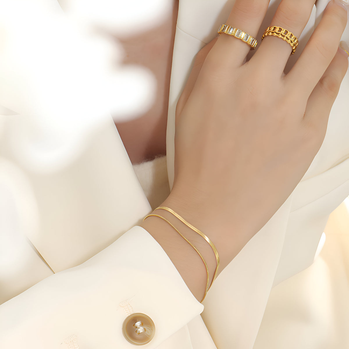 Bracelet double rang en titane plaqué or, finition lisse et chaîne fine élégante, porté au poignet féminin.