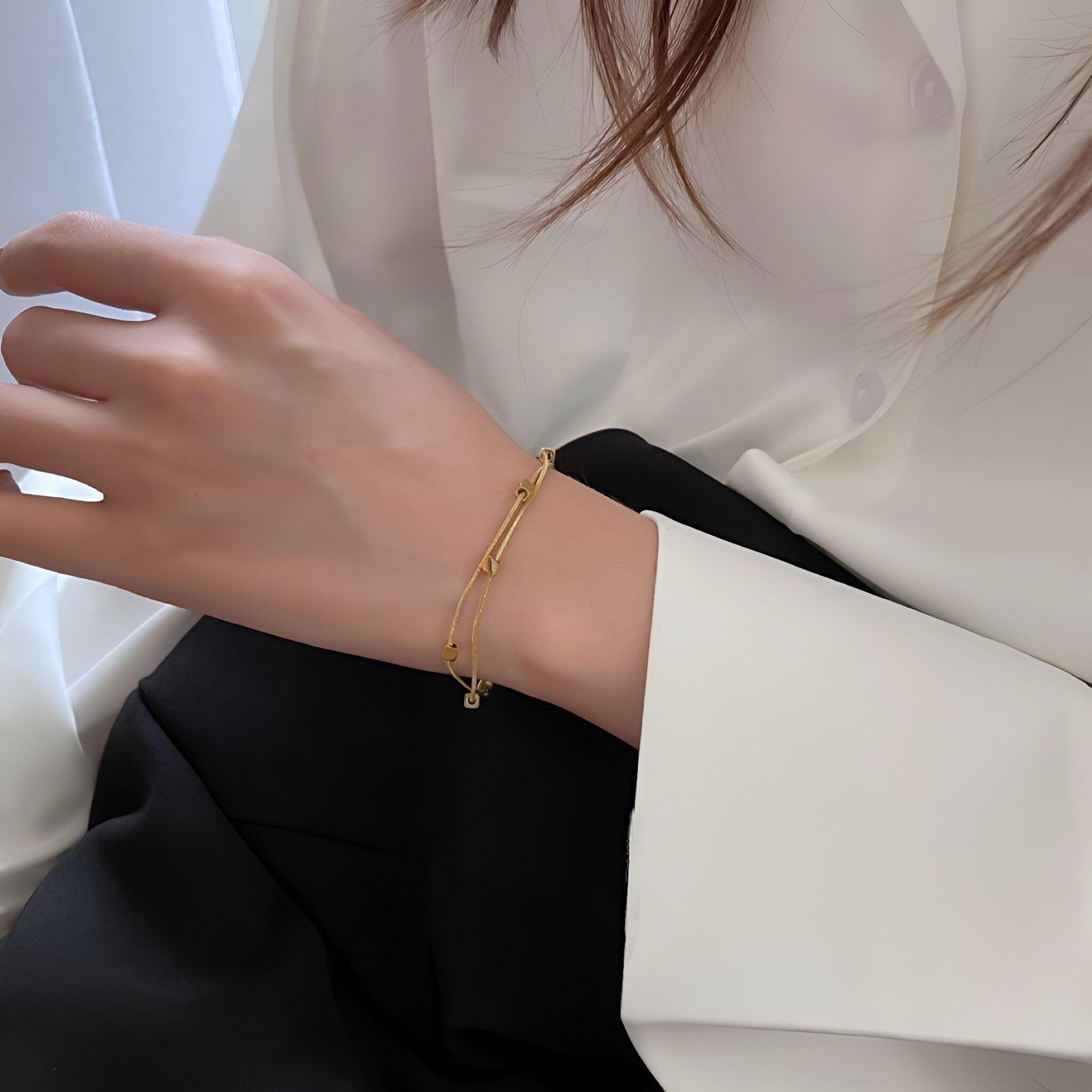 Bracelet double en titane plaqué or à motif petits cubes porté sur poignet féminin, style élégant et minimaliste.