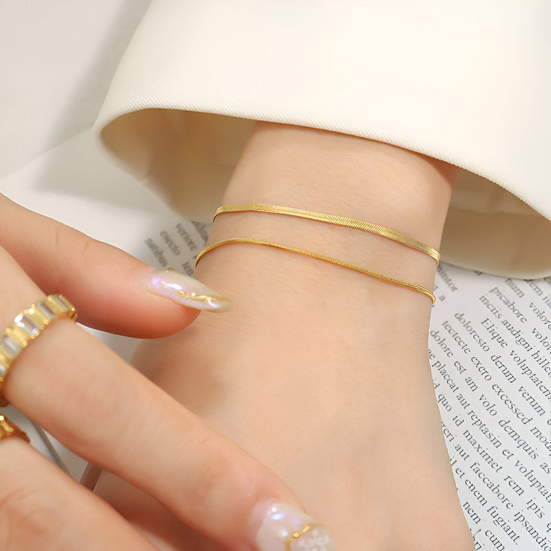 Bracelet double rang en titane plaqué or fin et élégant porté au poignet féminin.