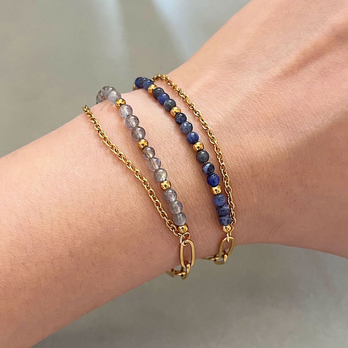 Bracelet double rang avec perles bleues et grises en pierres naturelles, chaîne fine dorée et fermoir mousqueton.