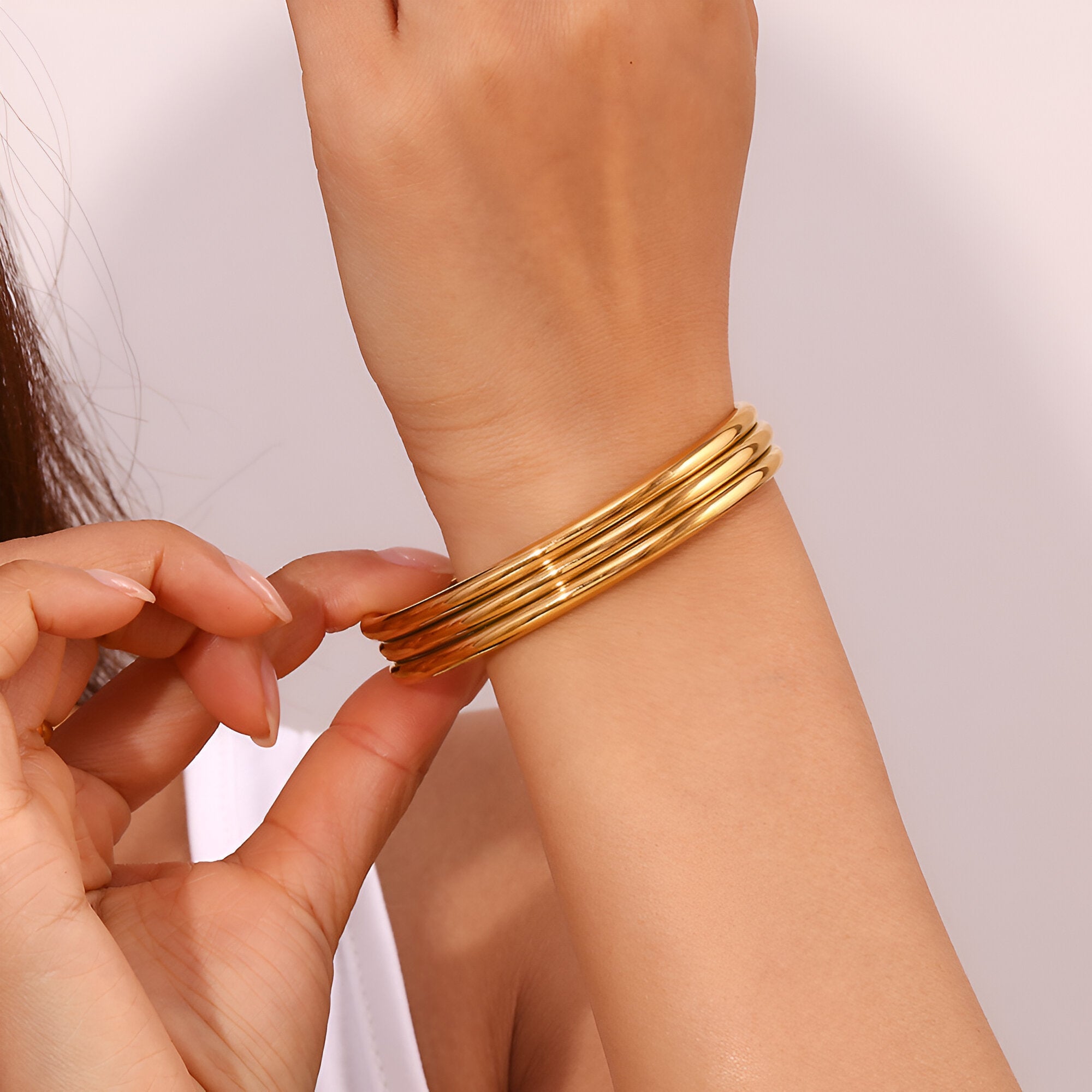 Bracelet trilogie d'anneaux en acier inoxydable plaqué or 18 carats, design lisse et brillant.