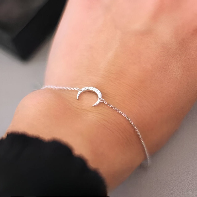 Bracelet fin en acier inoxydable argenté avec pendentif lune délicate pour femme.