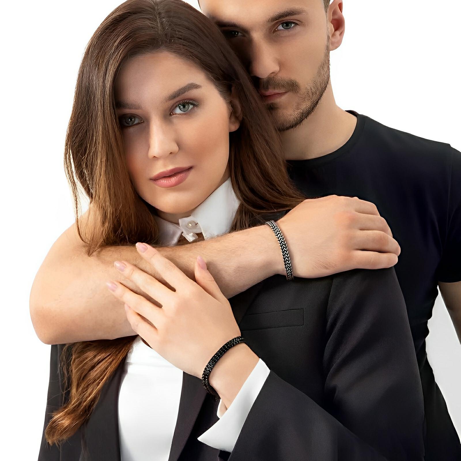 Bracelet en acier inoxydable noir à maille spiga fine, design moderne, porté au poignet homme et femme.