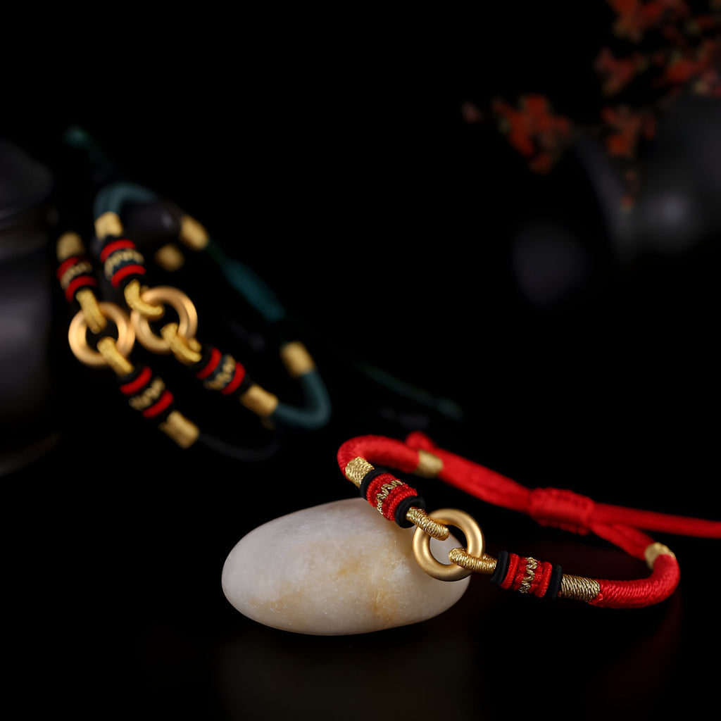 Bracelet en argent sterling et cercle doré avec cordon rouge et détails noirs et rouges.