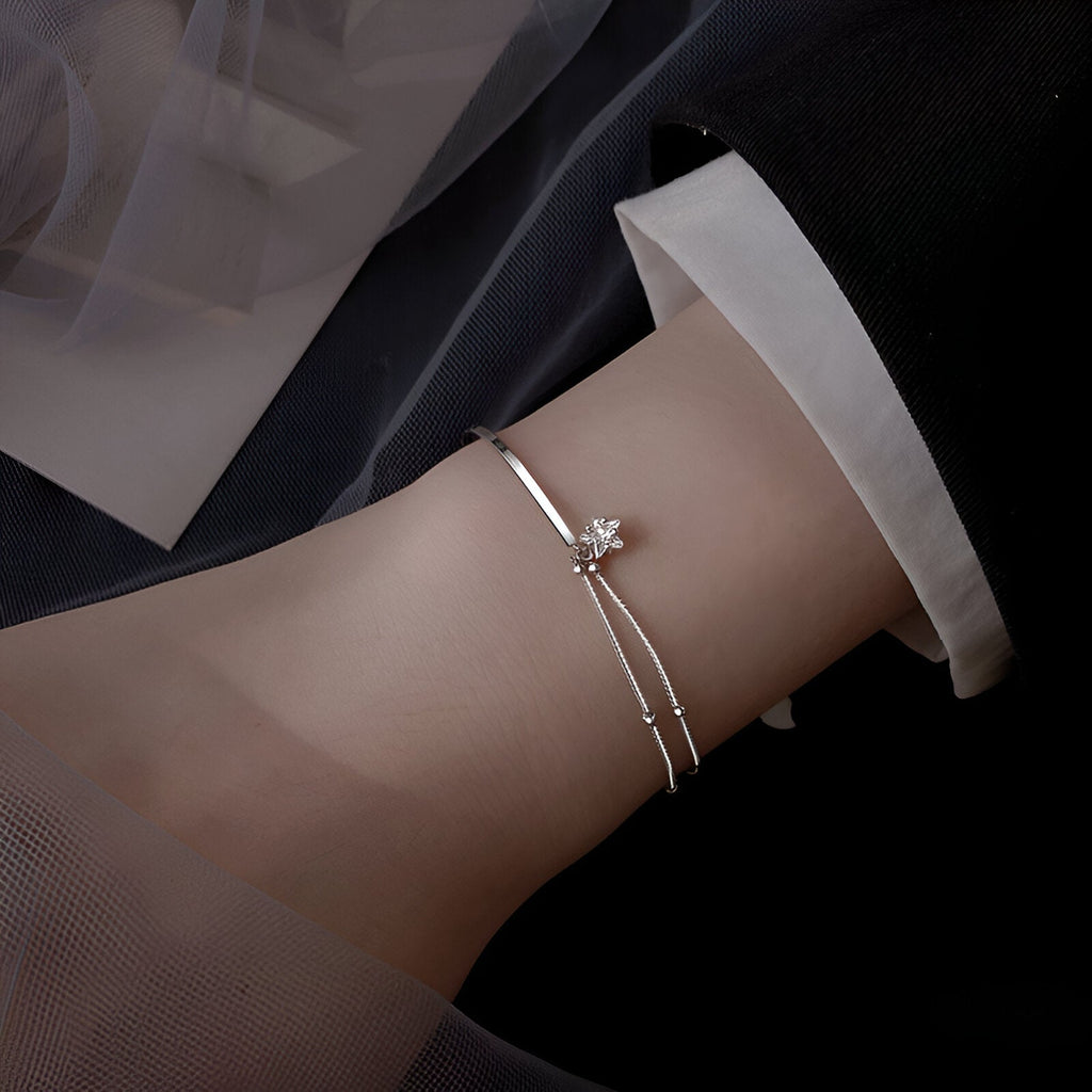 Bracelet fin en argent sterling avec pendentif étoile étincelante porté au poignet féminin.