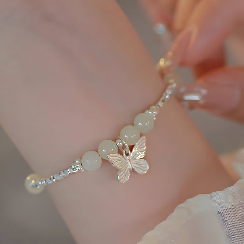 Bracelet argent sterling avec perles de jade blanches et breloque papillon délicate.
