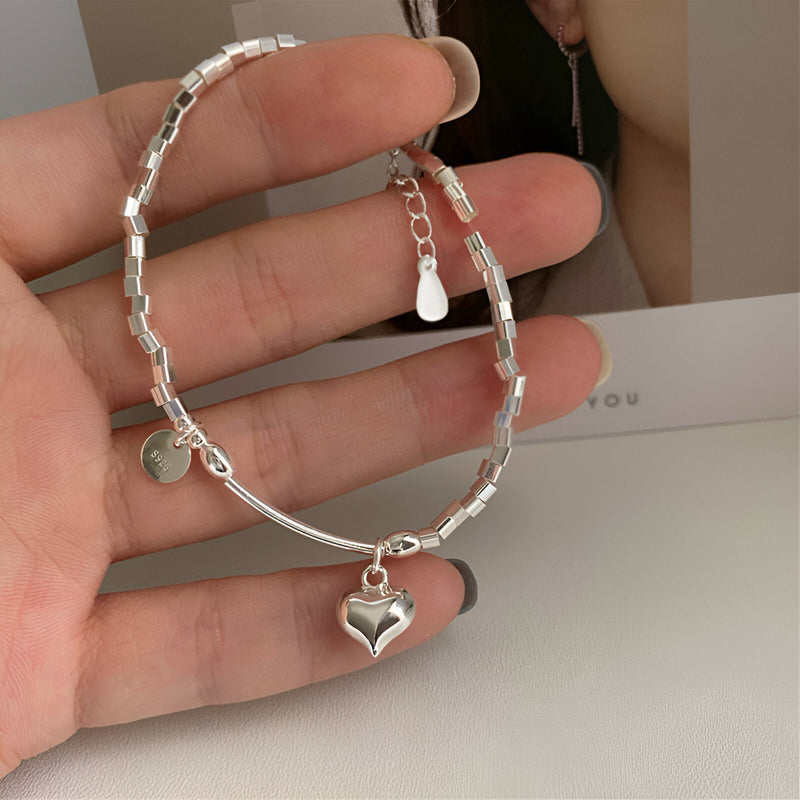 Bracelet en argent sterling pour femme avec perles cylindriques et pendentif cœur brillant.