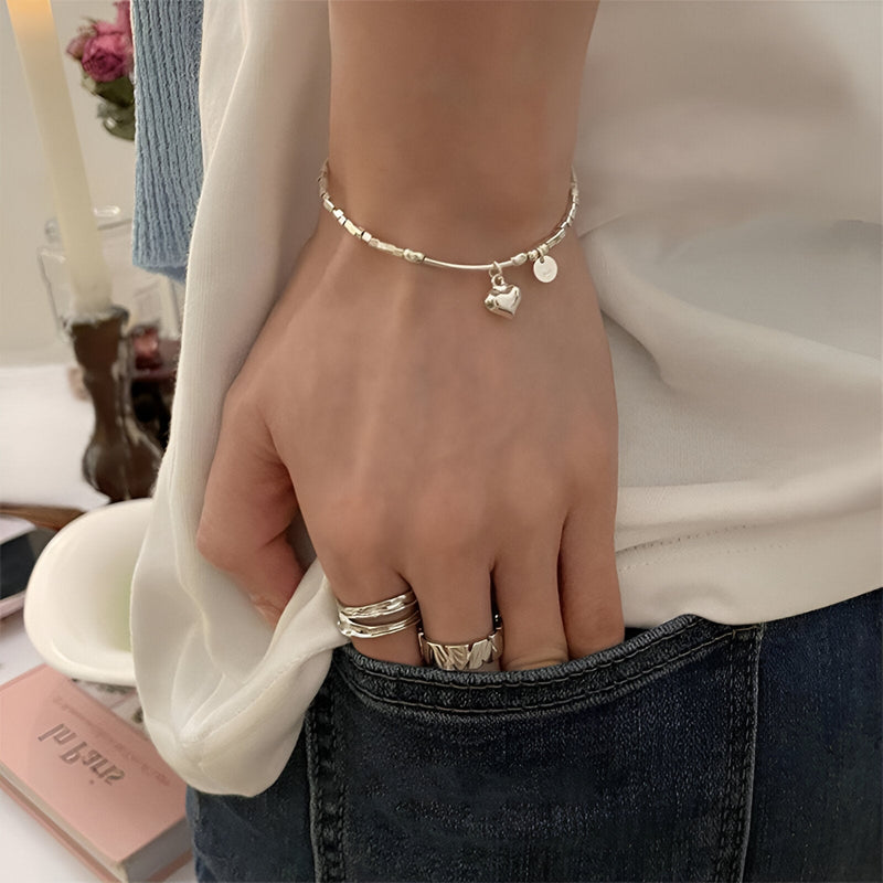 Bracelet fin en argent sterling avec pendentif cœur et étoile porté au poignet féminin.