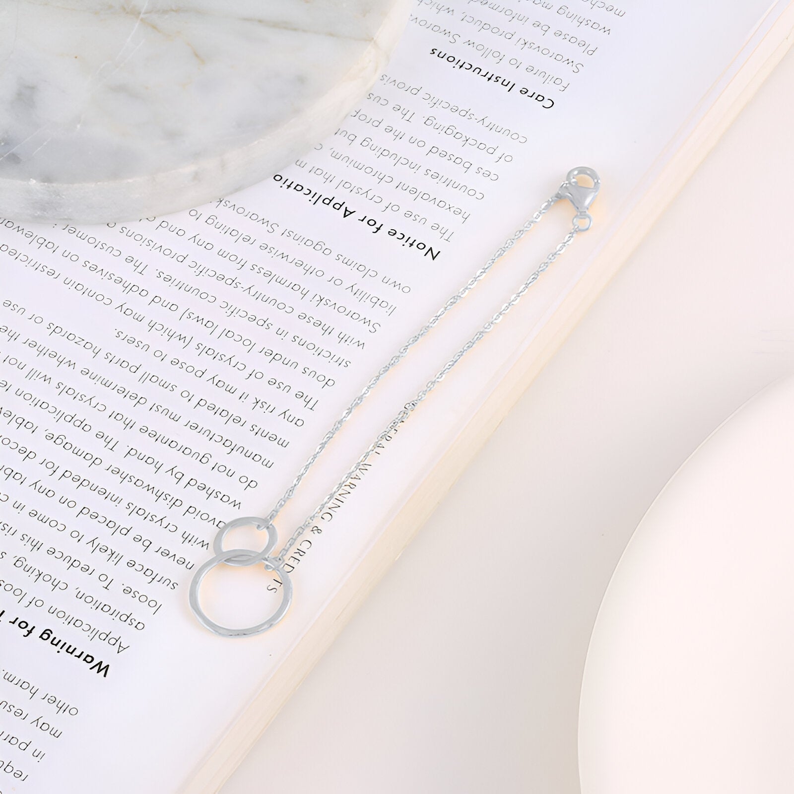 Bracelet en argent sterling pour femme avec deux cercles entrelacés et chaîne fine élégante.