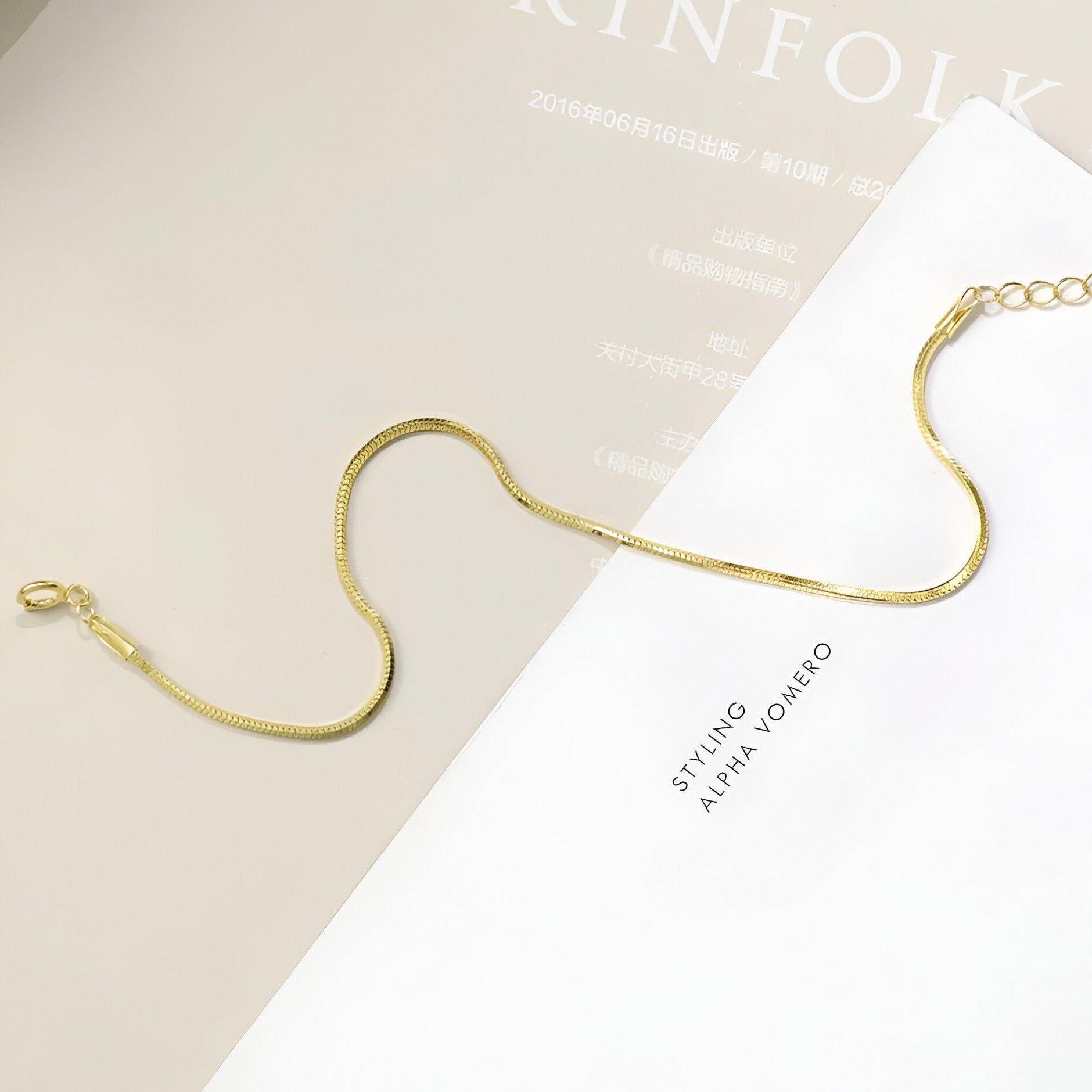 Bracelet fin en or jaune avec chaîne serpent et fermoir mousqueton, design élégant.