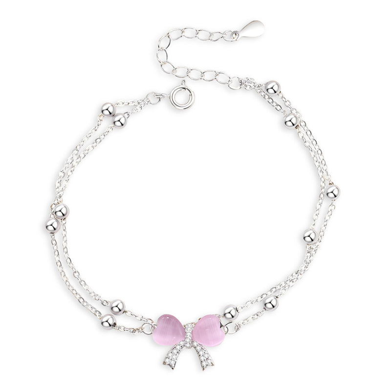 Bracelet en argent sterling avec double chaîne et noeud ruban rose orné de petits cristaux.