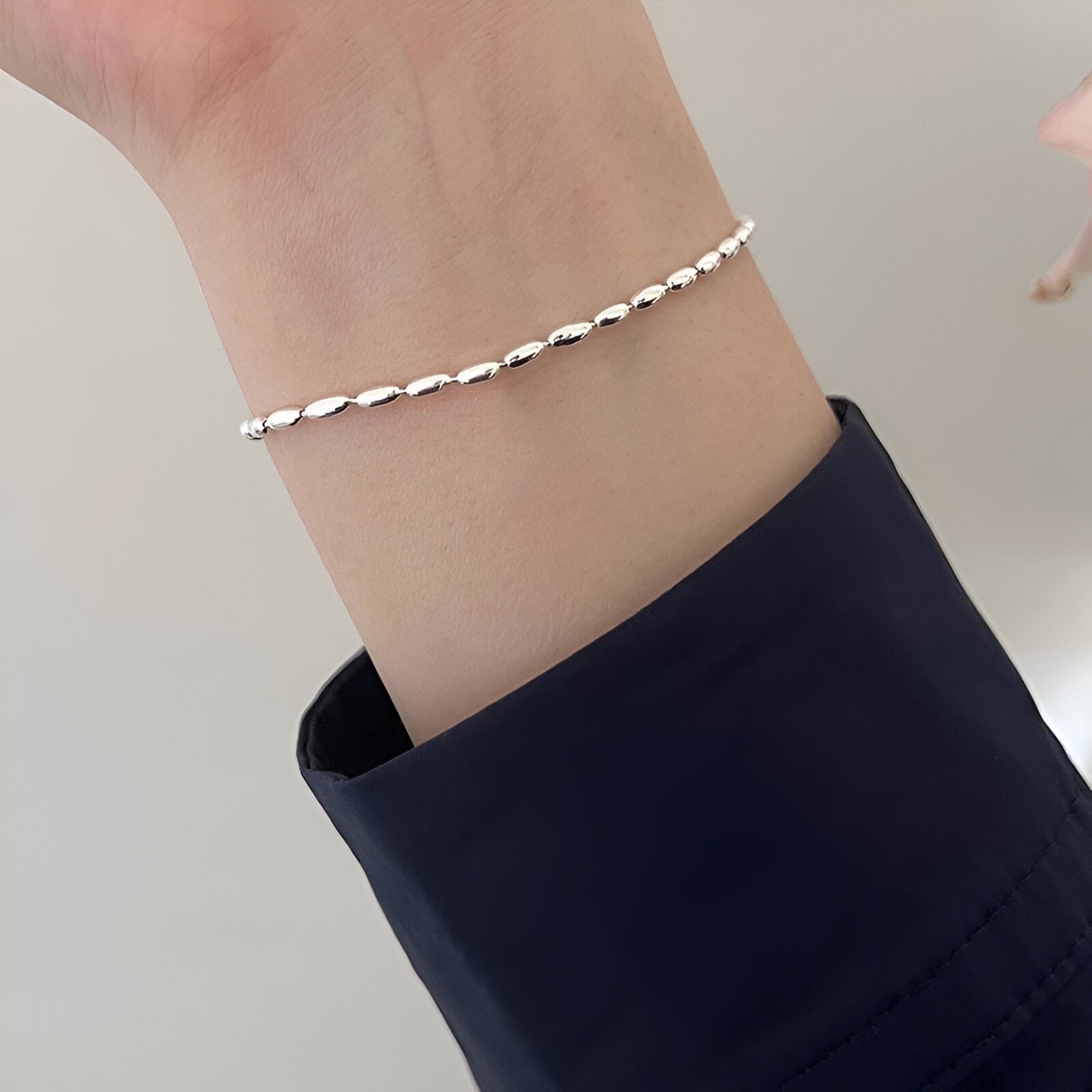 Bracelet fin en argent sterling à maillons grain de riz porté au poignet, style délicat pour femme.