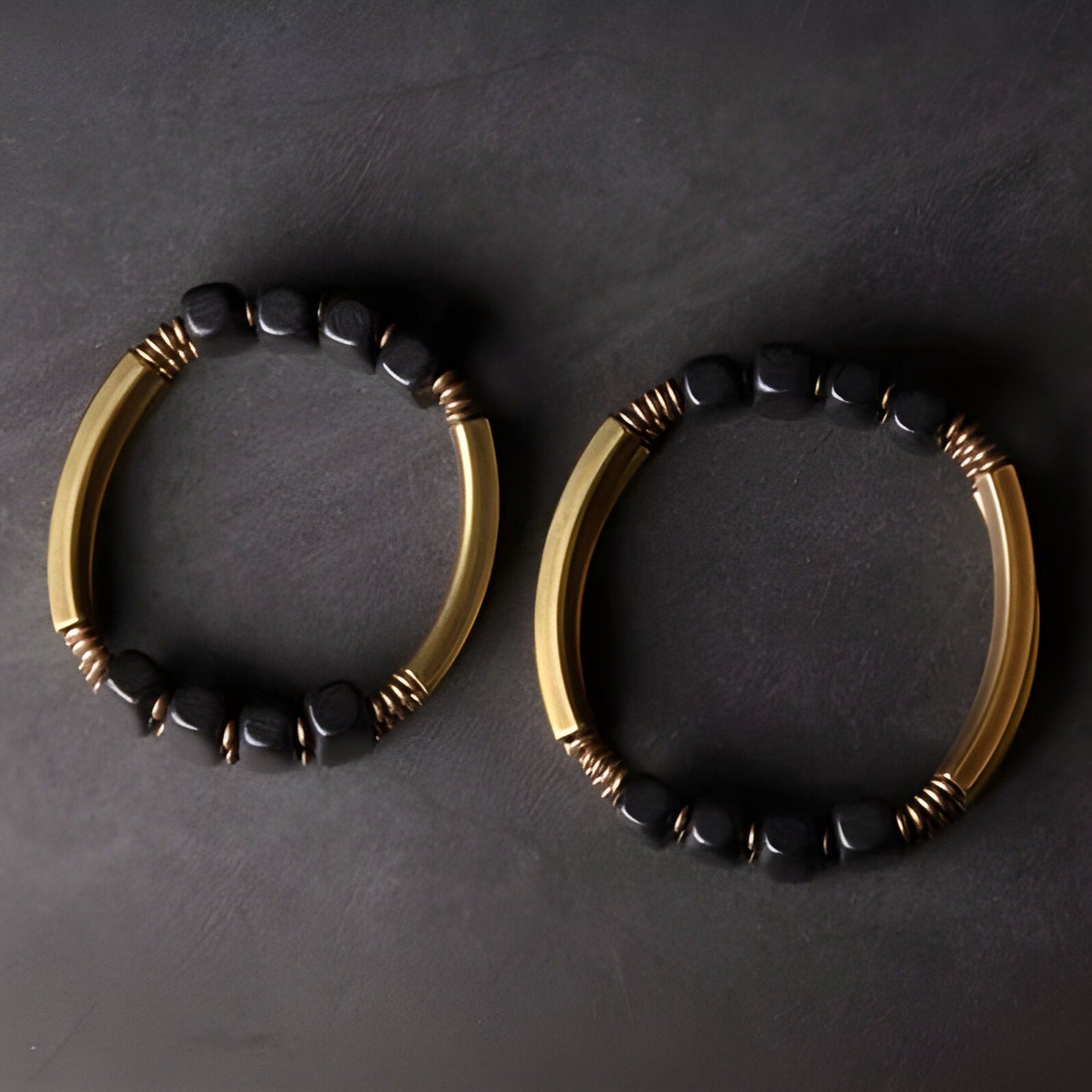Bracelet flexible pour femme en bois d’ébène noir avec tubes en cuivre doré.