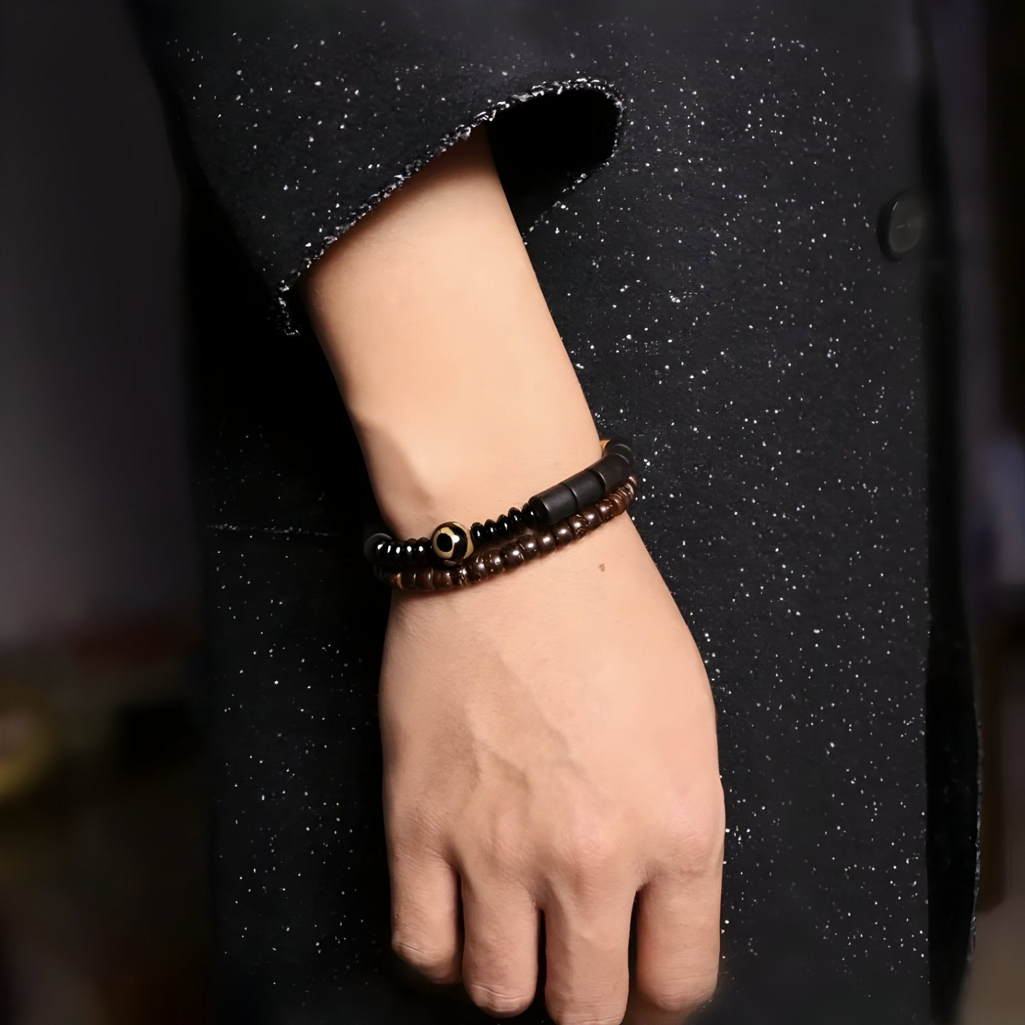 Bracelet mixte en bois d'ébène noir et perles d'obsidienne sur poignet, style naturel élégant.