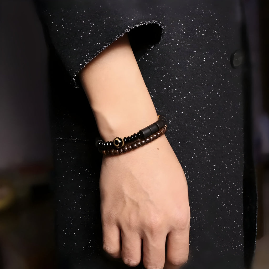 Bracelet mixte en bois d'ébène noir et perles d'obsidienne sur poignet, style naturel élégant.