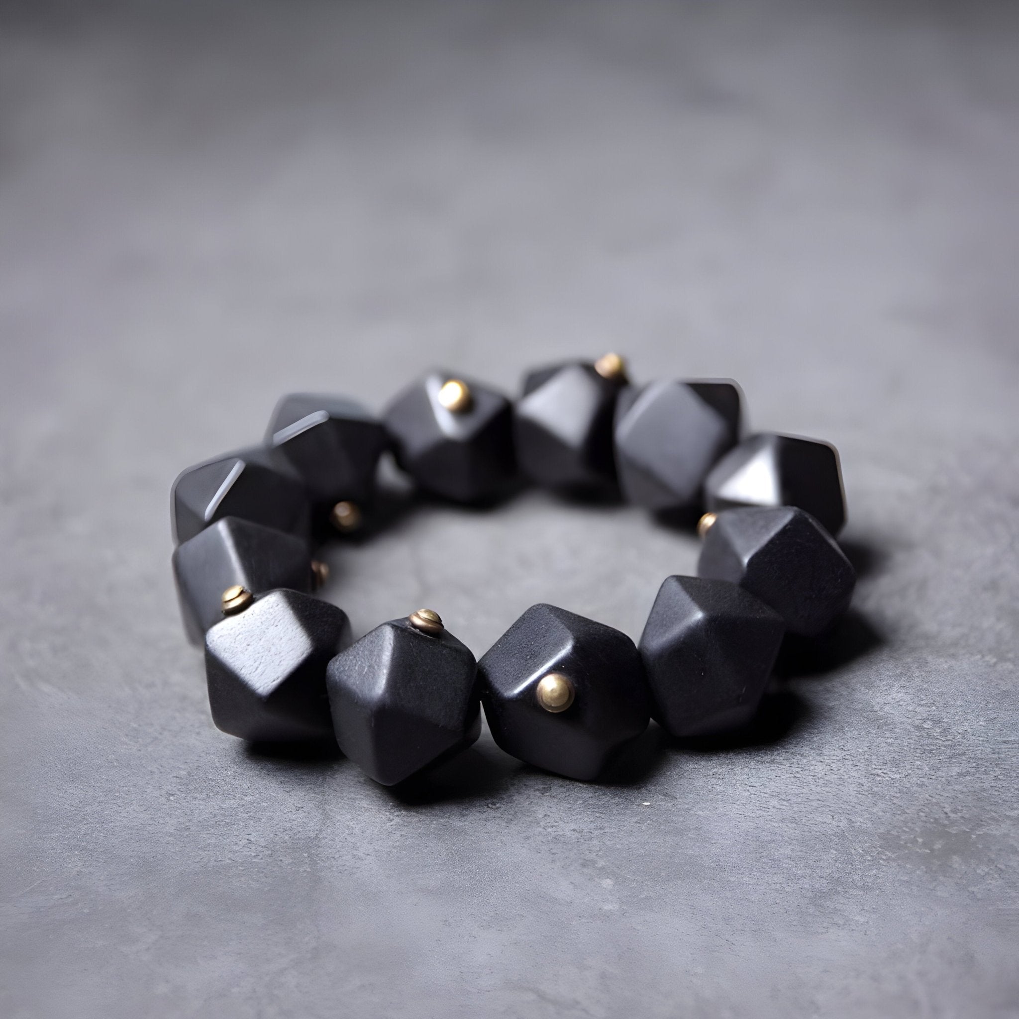 Bracelet femme en bois d’ébène noir mat avec perles dorées entre chaque facette géométrique.