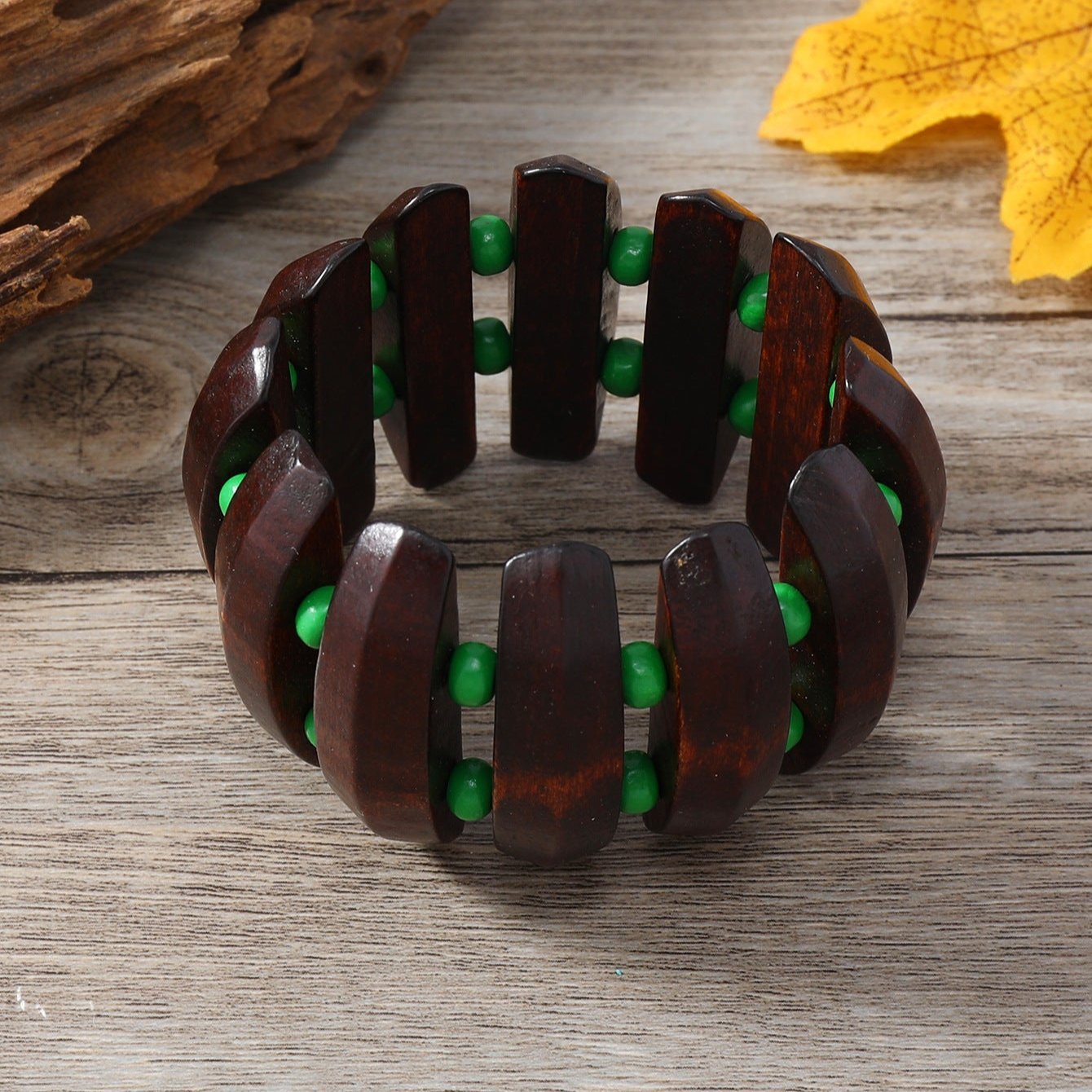 Bracelet large en bois foncé avec perles vertes, style naturel et audacieux pour femme.