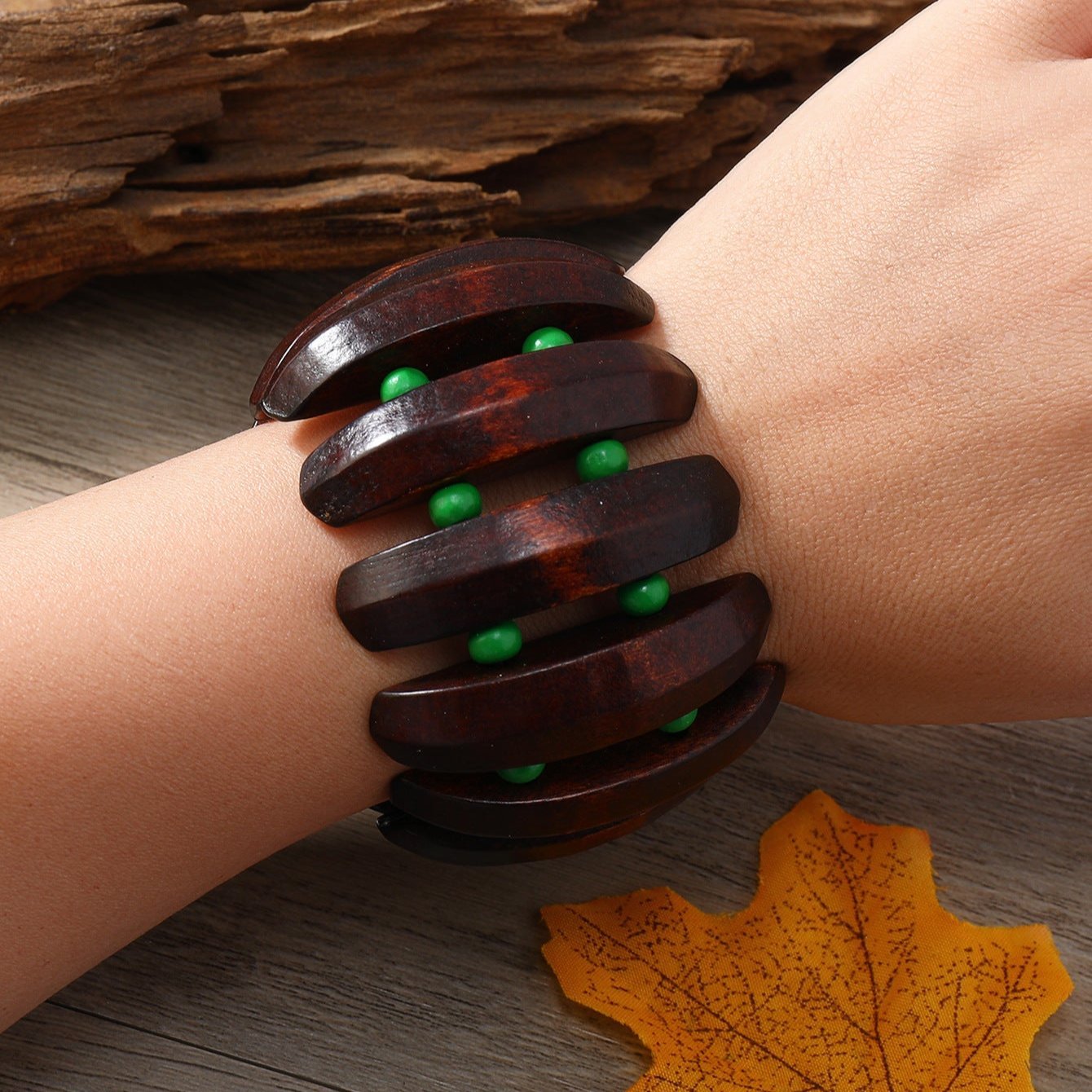 Bracelet large en bois foncé avec perles vertes, style audacieux pour femme.