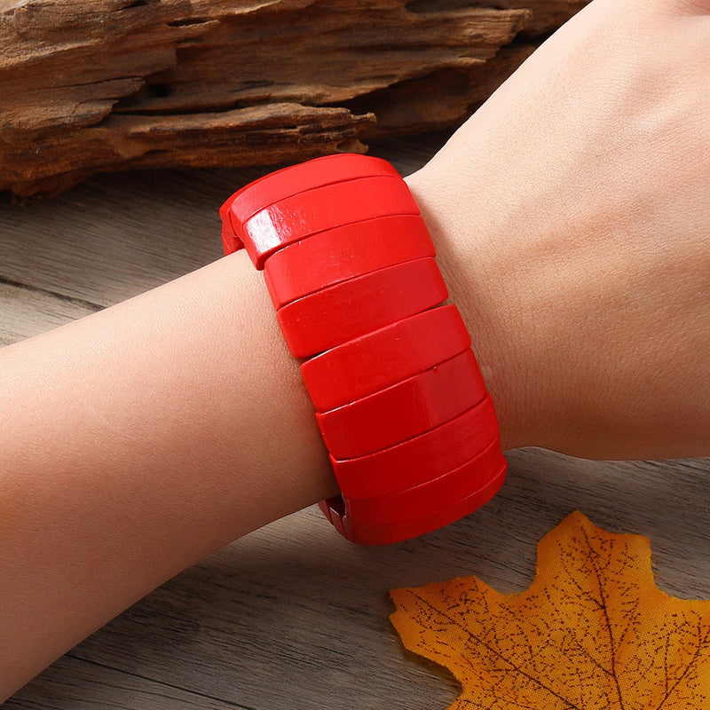 Bracelet large en bois rouge vif, segments lisses et incurvés, style automnal élégant.