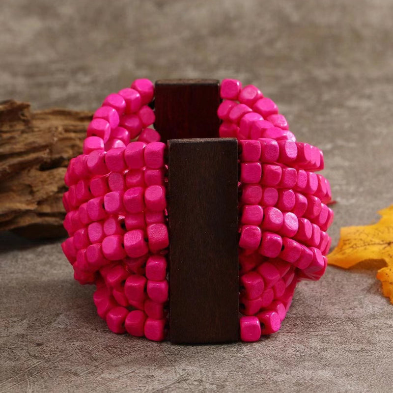 Bracelet femme en bois naturel avec perles roses vif et bande centrale en bois foncé.