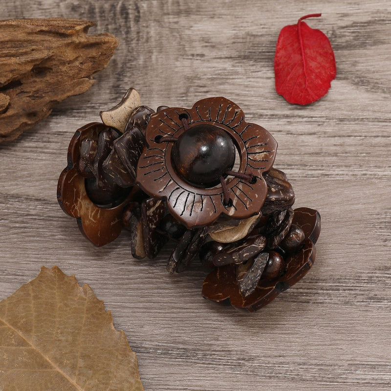 Bracelet femme en bois naturel couleur café avec fleurs sculptées et perle centrale noire.