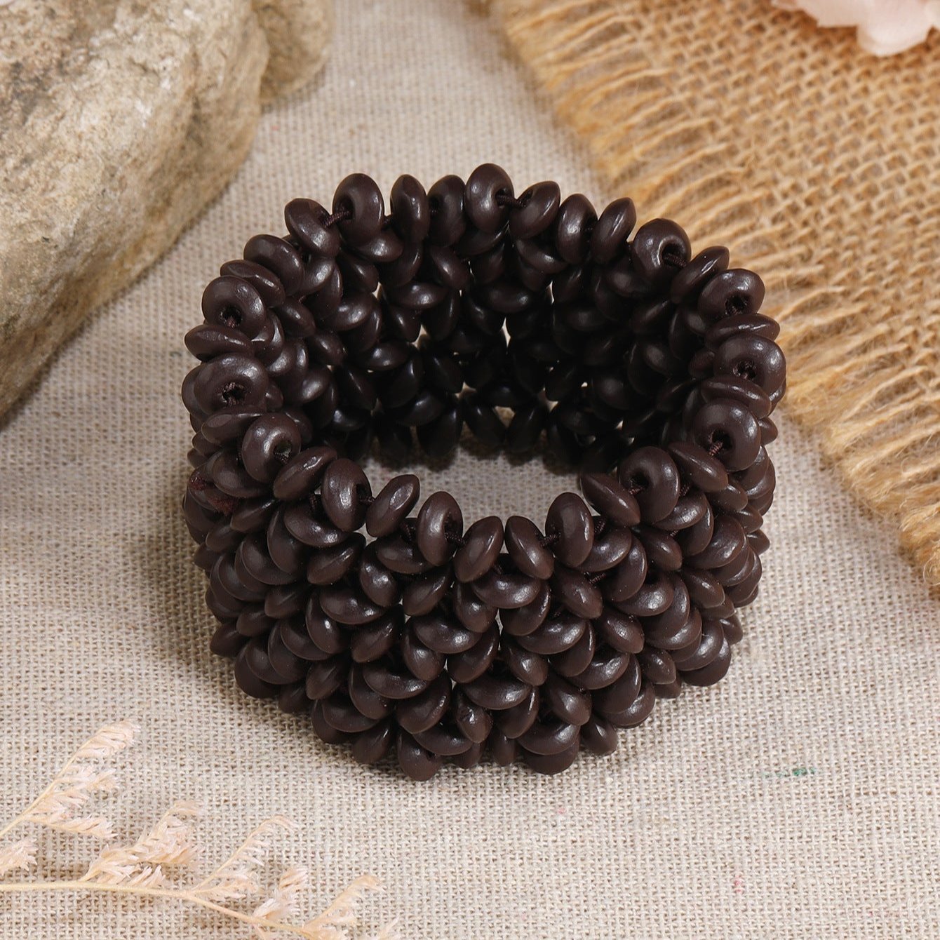 Bracelet femme en bois naturel café avec motif de petites fleurs sculptées, style large et texturé.