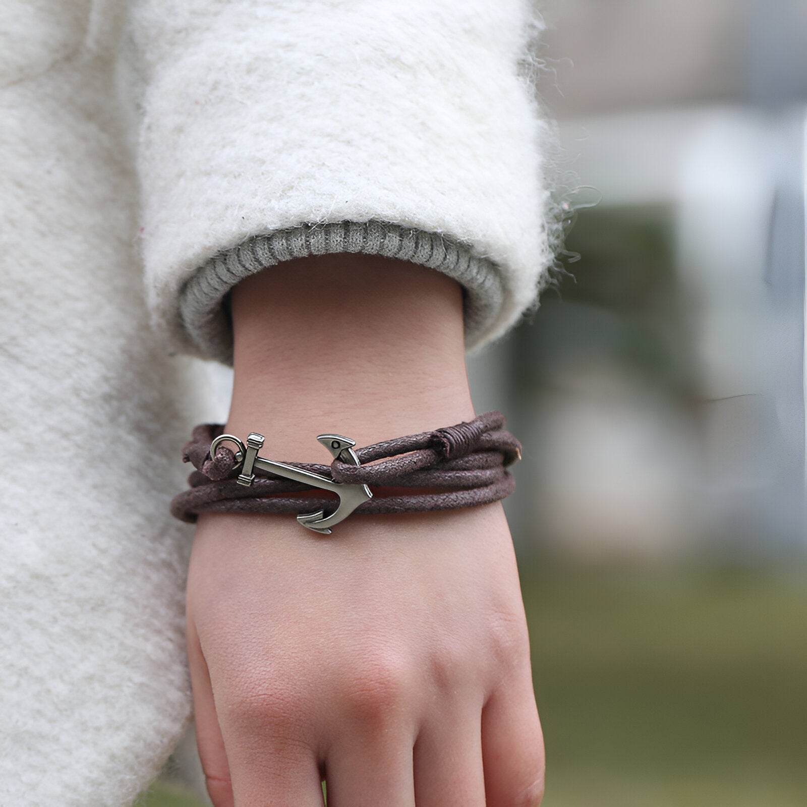 Bracelet en corde café à motif ancre en métal vieilli porté au poignet féminin.