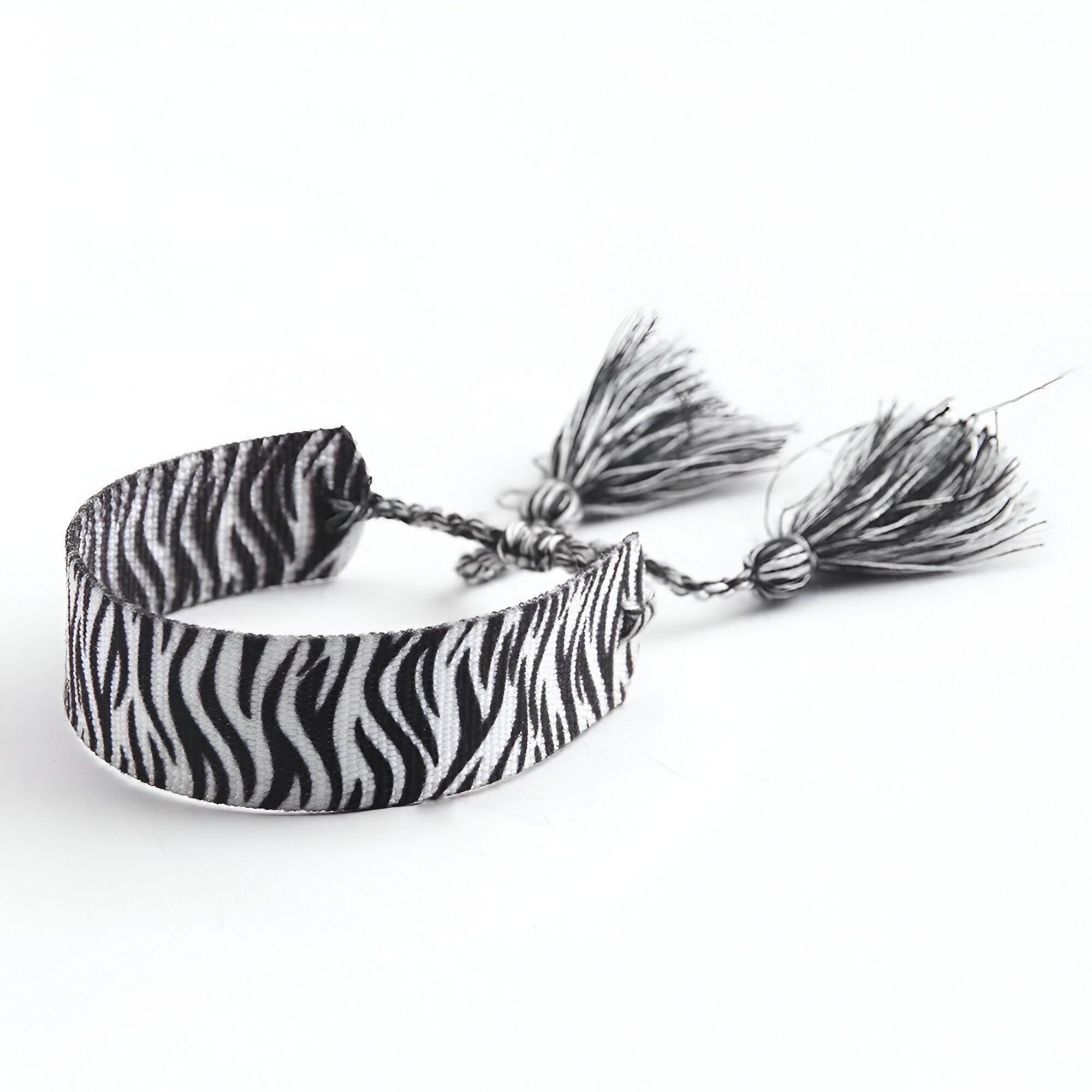 Bracelet en corde tressée blanc à motif zèbre noir avec pompons assortis.