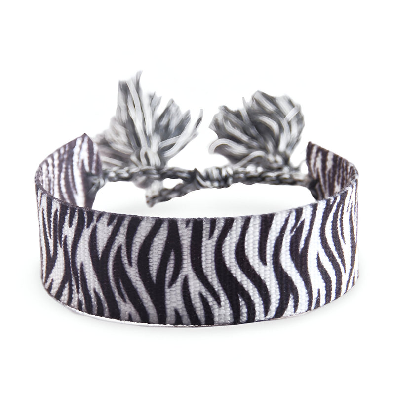 Bracelet en corde tressée avec motif zèbre noir et blanc et pompons assortis.
