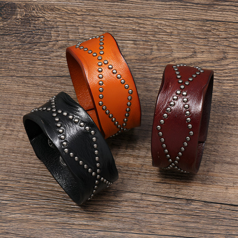 Bracelet en cuir clouté orange style western avec motif croisé d'anneaux métalliques.