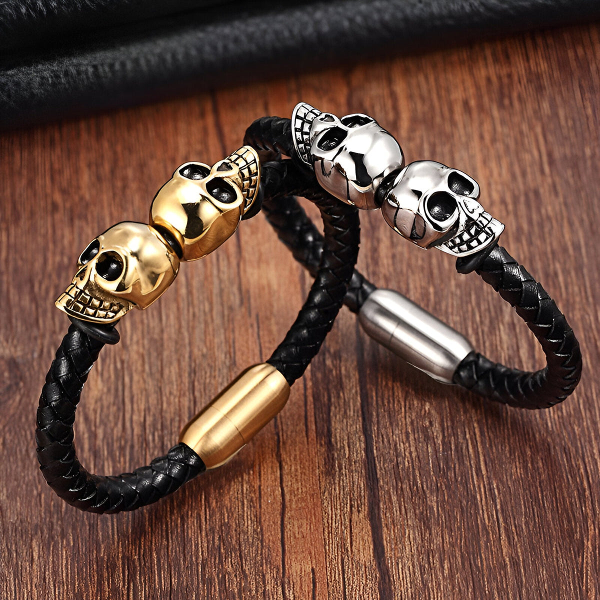 Bracelet en cuir noir tressé avec double tête de mort en métal doré et fermoir aimanté doré et argenté.