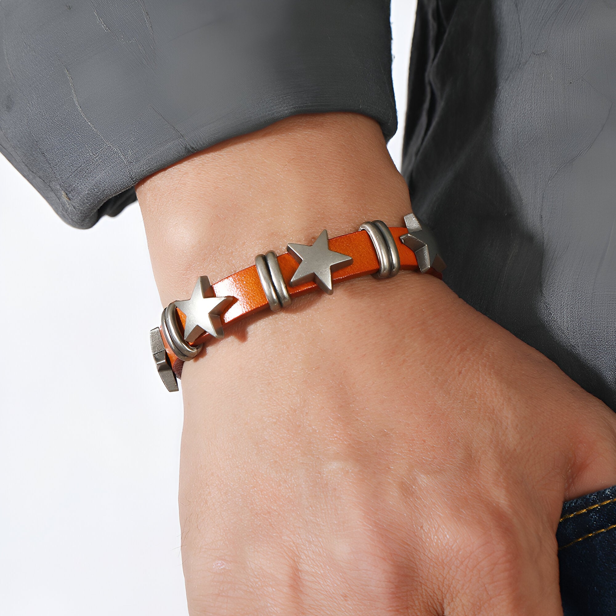 Bracelet en cuir orange pour homme avec étoiles métalliques argentées et détails noirs.