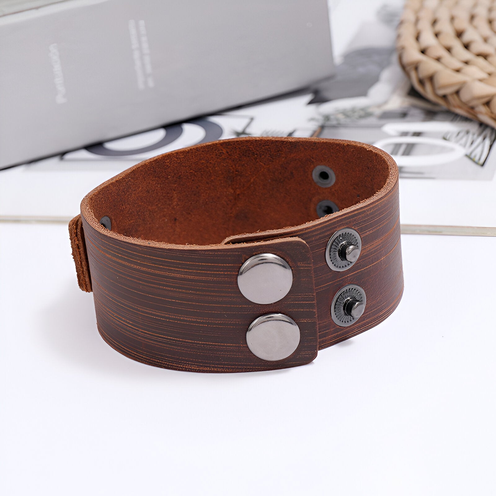 Bracelet en cuir marron avec motif hache gravé et fermeture à boutons-pression métalliques argentés.
