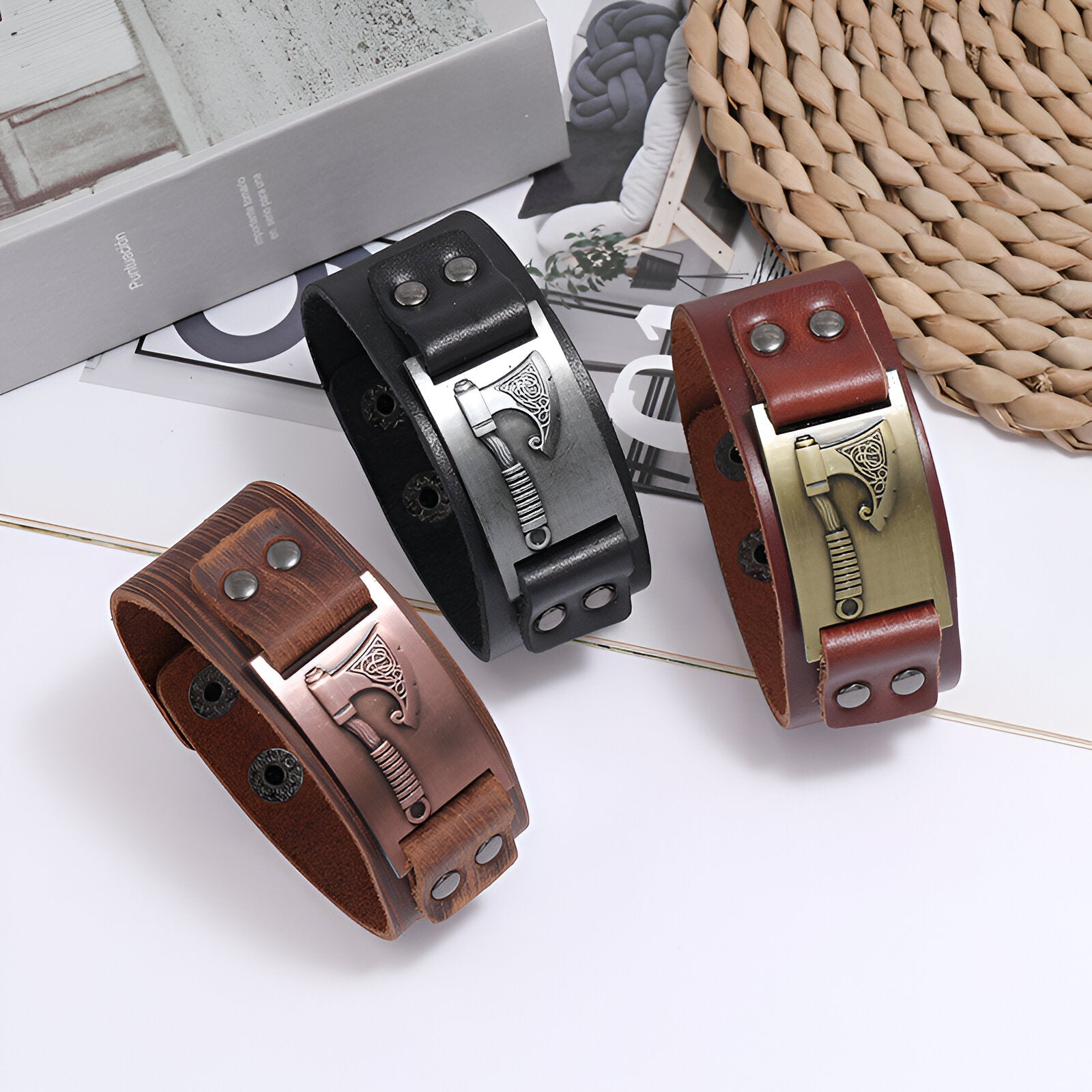 Trois bracelets en cuir noir, marron et café avec motif hache en métal gravé et boutons-pression métalliques.