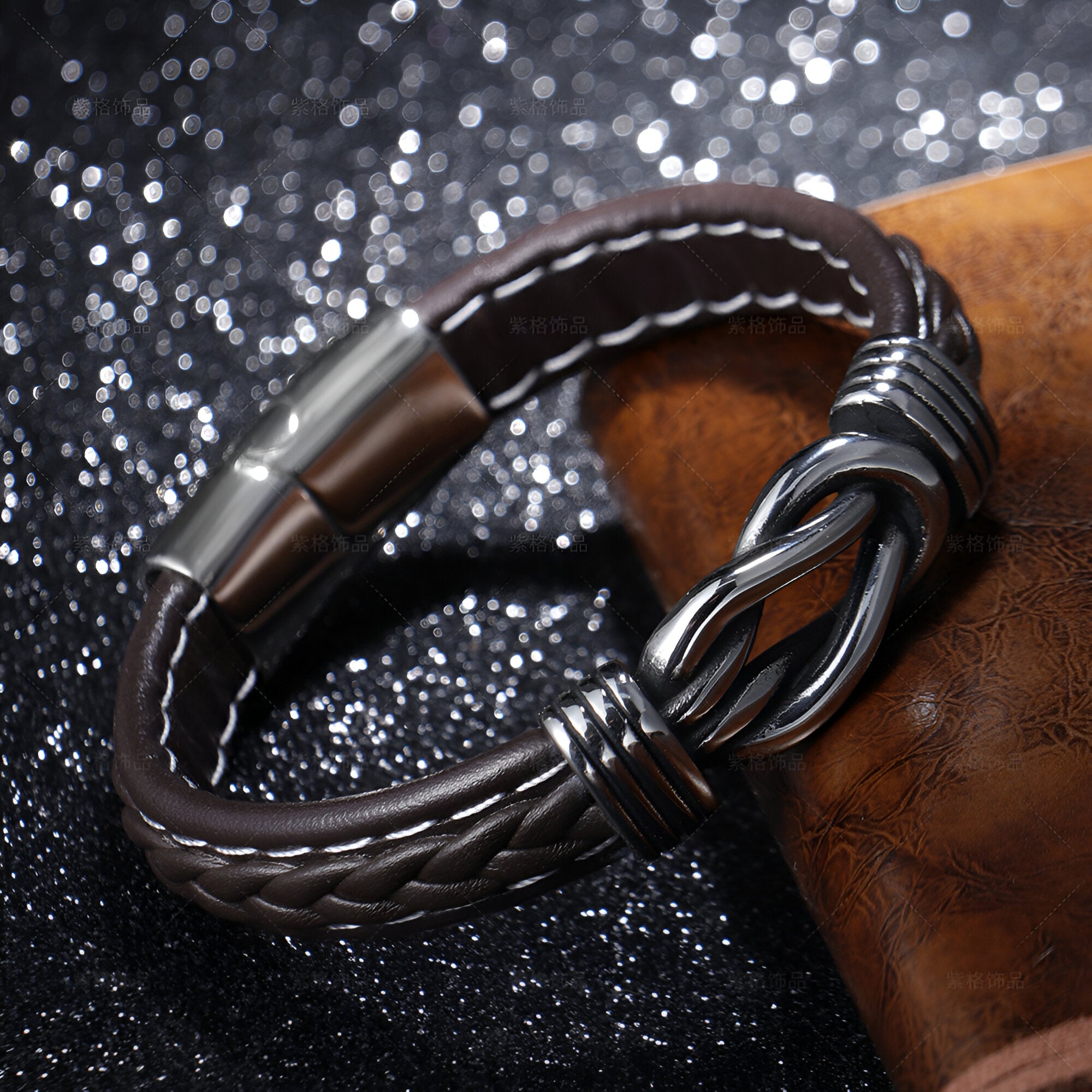 Bracelet en cuir noir tressé avec fermoir métallique et nœud décoratif élégant.