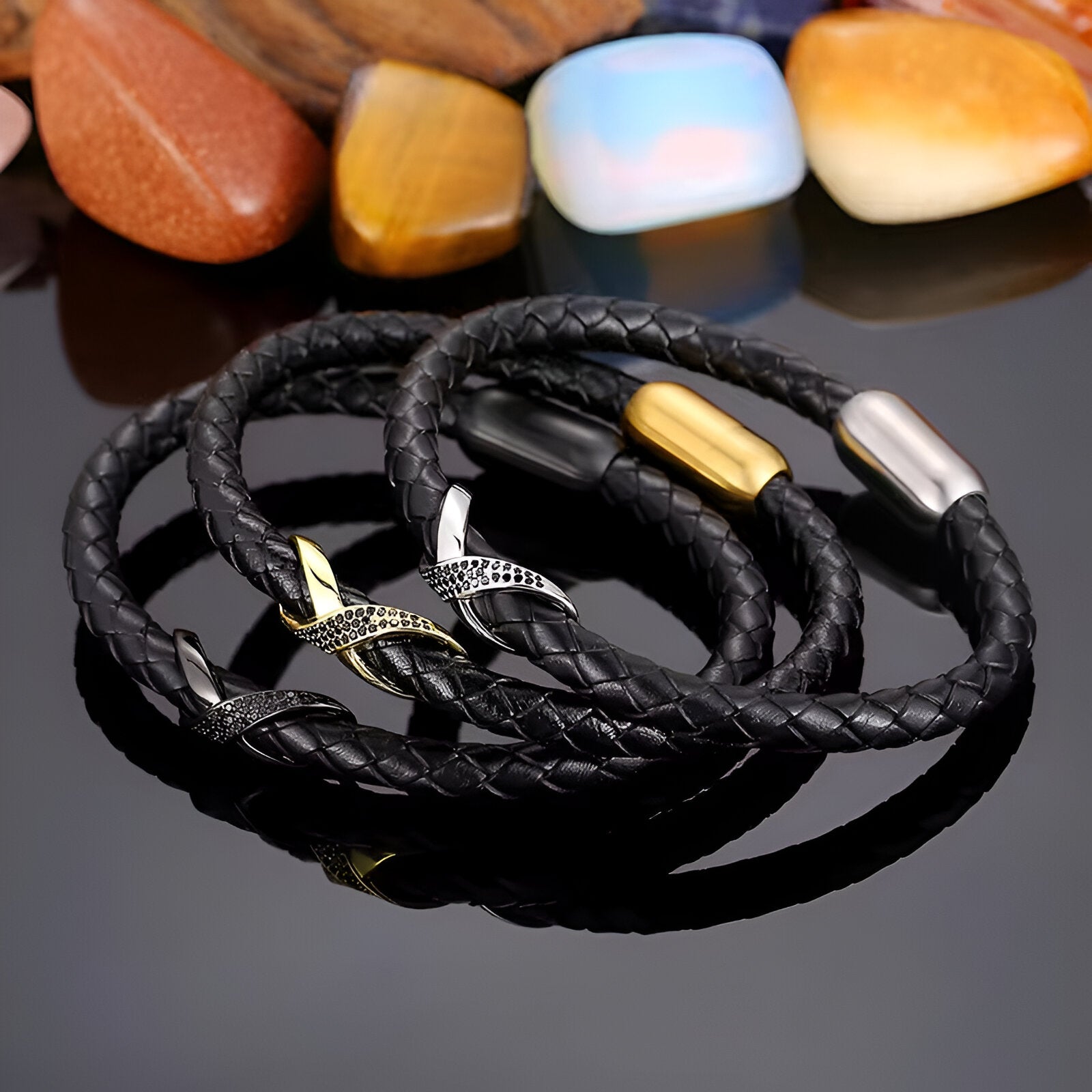 Bracelet en cuir noir tressé avec nœud central en acier doré et argenté, fermoir magnétique assorti.