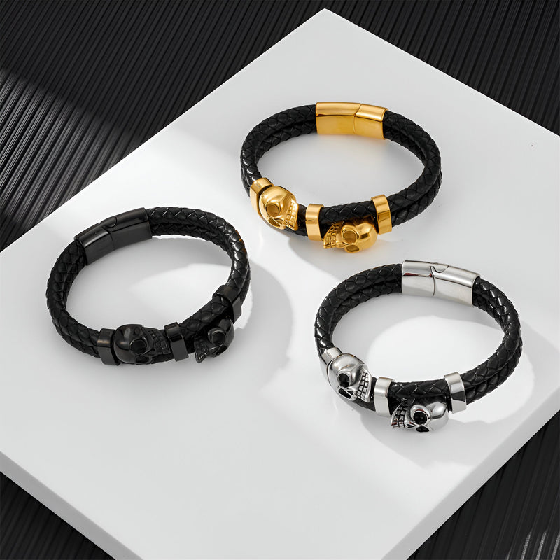 Trois bracelets en cuir noir tressé avec ornements double têtes de mort en argent, noir et or.