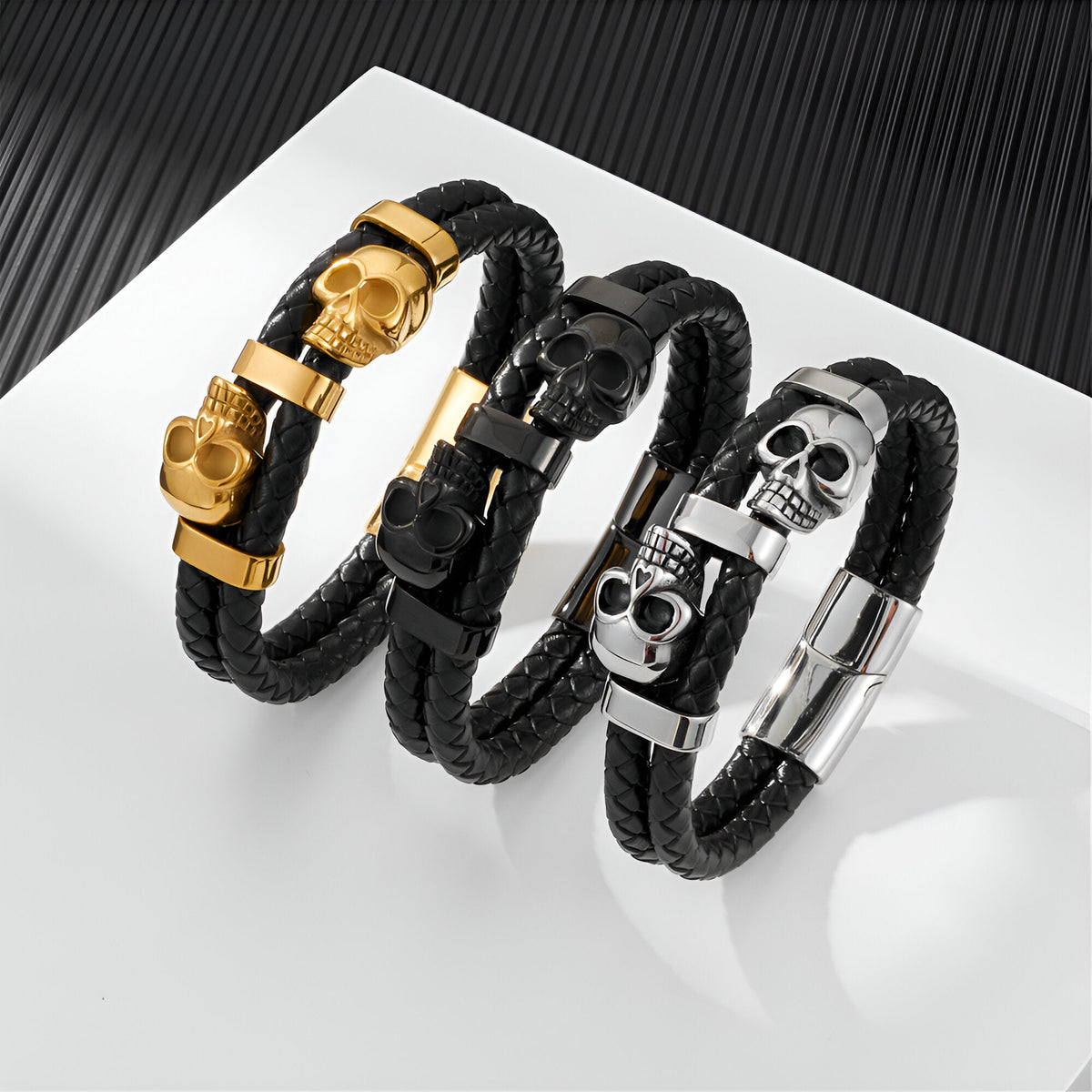 Bracelet en cuir noir tressé avec ornement double têtes de mort en métal or, noir et argent.
