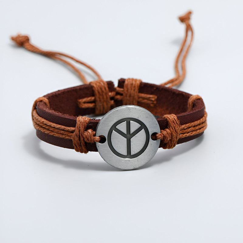 Bracelet en cuir marron avec médaille ronde en métal gravée du symbole de la paix, lacets réglables en corde beige.