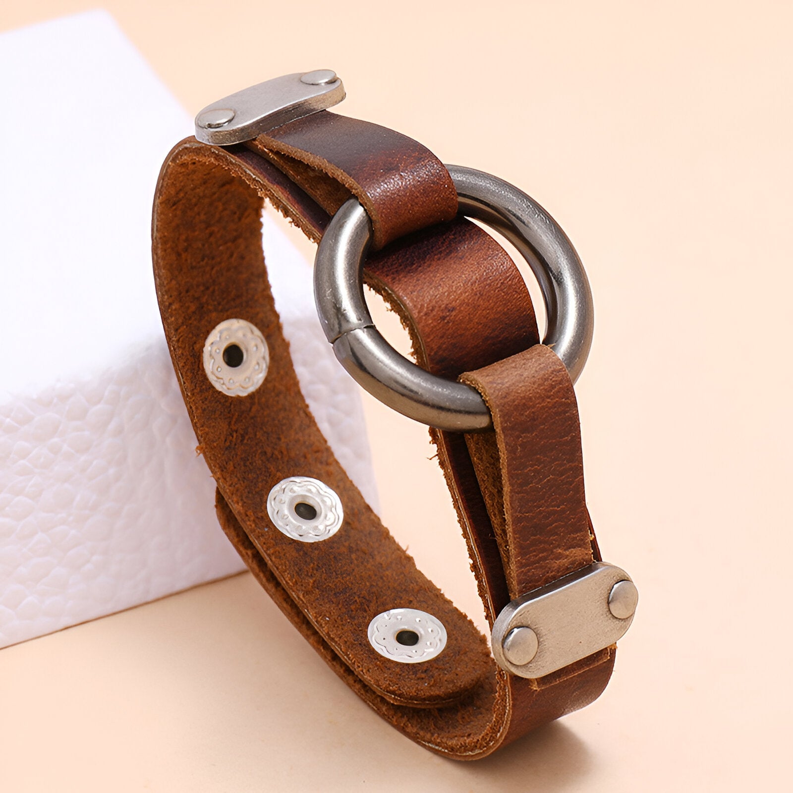 Bracelet en cuir marron pour homme avec anneau métallique argenté et fermoir à pression.