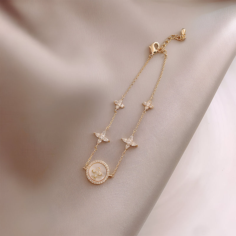 Bracelet fin en cuivre plaqué or avec trèfles à 4 feuilles et cercle orné de strass, fermoir ajustable.