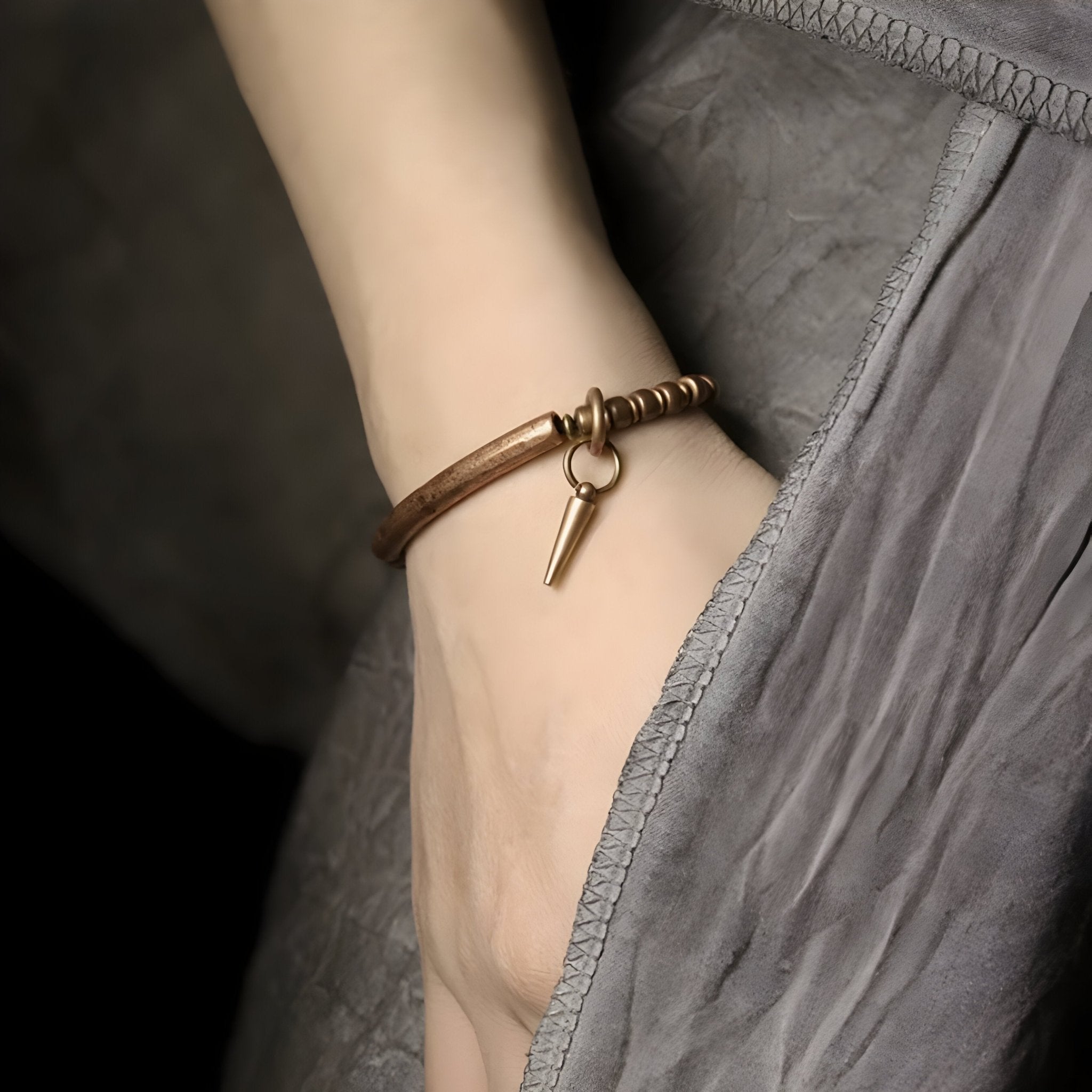 Bracelet fin en cuivre marron avec pendentif clé minimaliste sur poignet féminin.