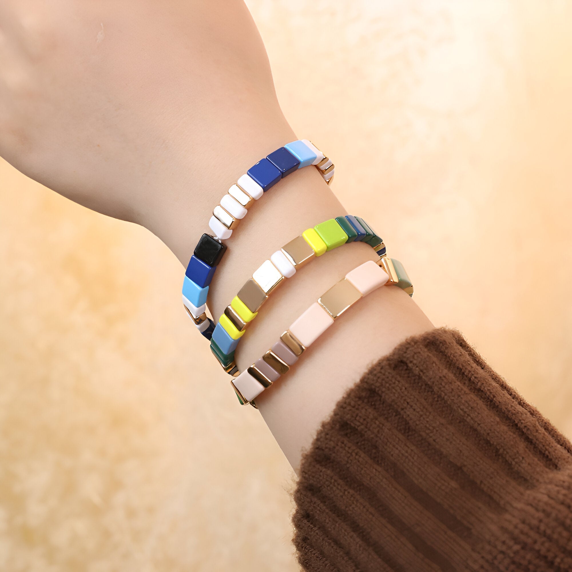 Trois bracelets en émail aux couleurs vives et carrés, modèles Calypso, portés sur un poignet feminine.